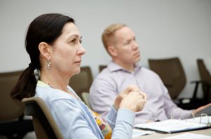 Adult learners sitting at a table listening to a lecture