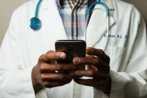Close-up of a doctor typing on his cellphone